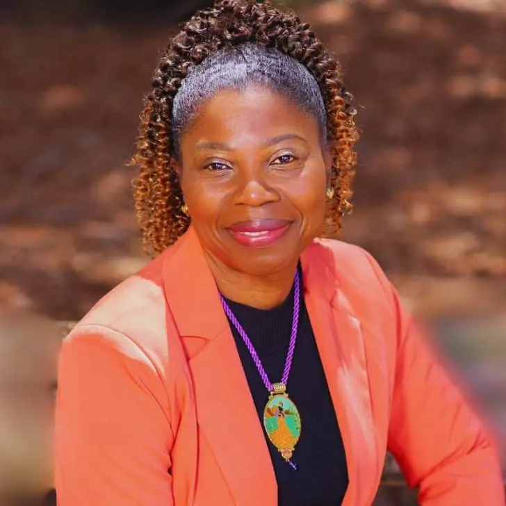 African American Professional coach, looking directly at the camera smiling wearing an orange blazer